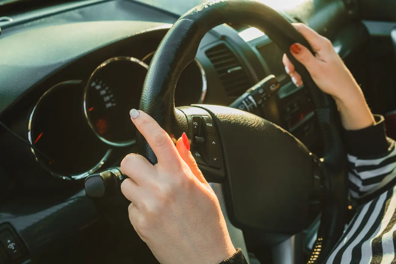 female hands on black steering wheel of modern car 2023 11 27 04 49 35 utc